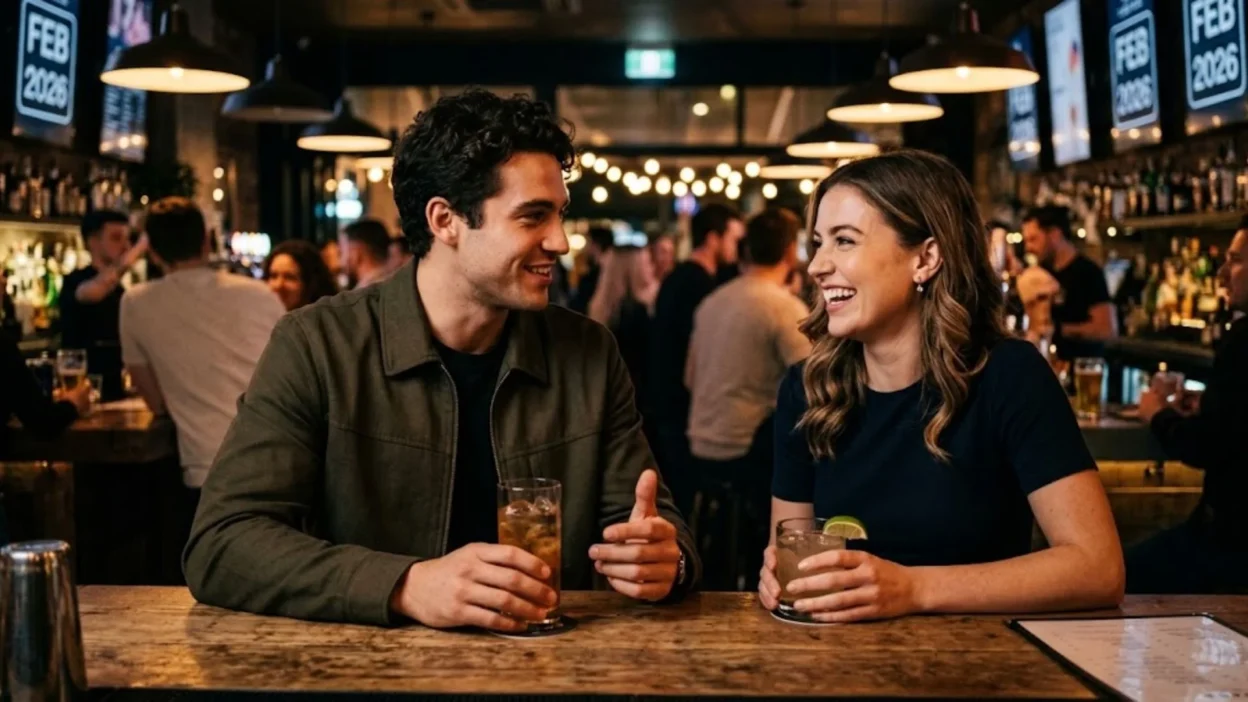 Man and woman smiling and sharing drinks at a warm ambient bar counter